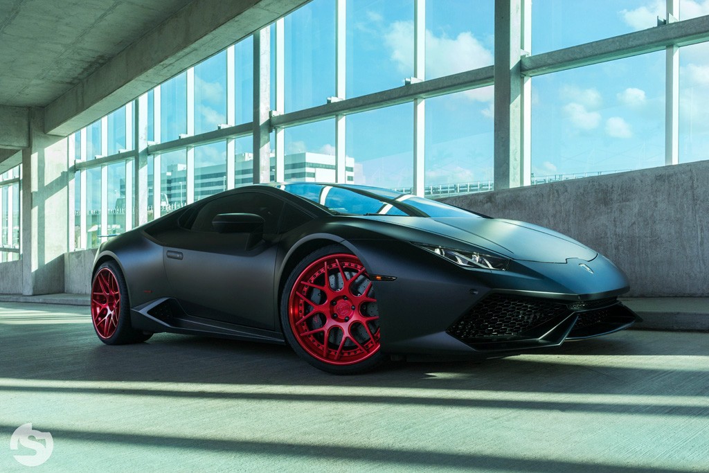 Un Lamborghini negro mate con llantas de color rojo vivo