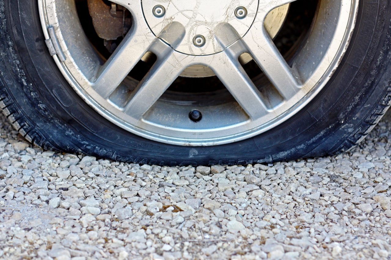 Close Up On Flat Car Tire On Gravel Road