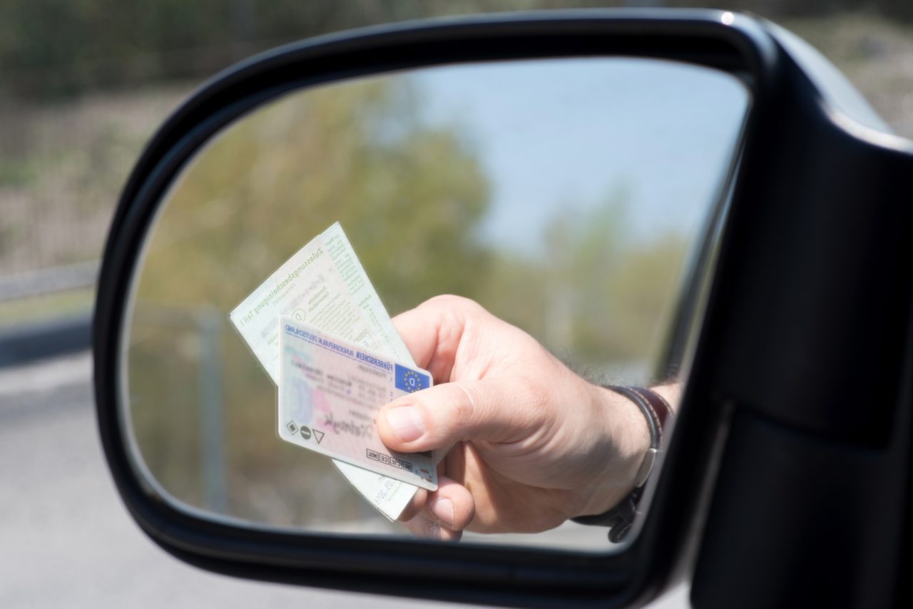 A Man Shows Driver's License And Vehicle License During A Check